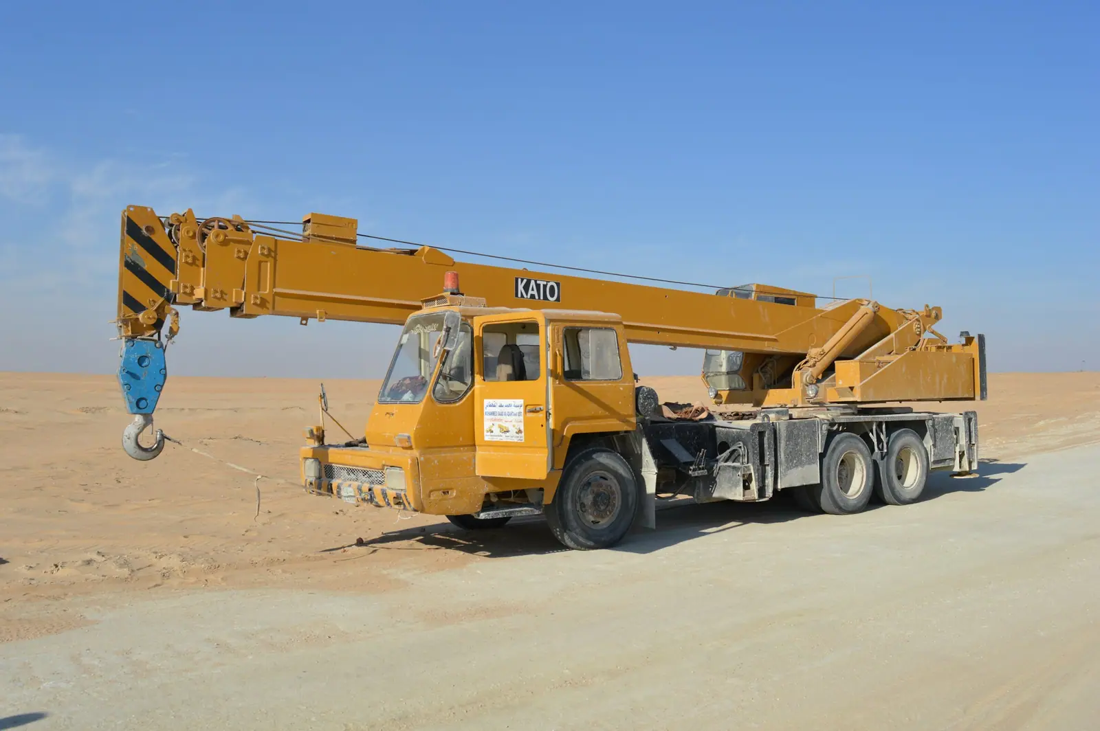 Truck-mounted mobile crane on open desert ground