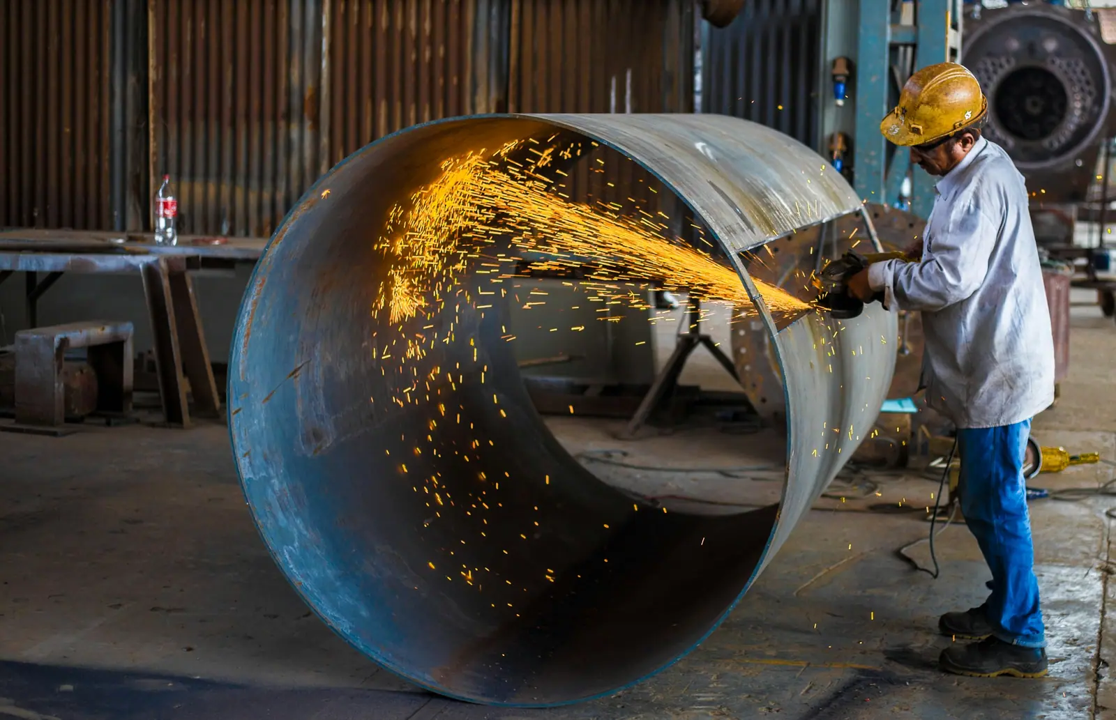 Technician grinding a large steel pipe section